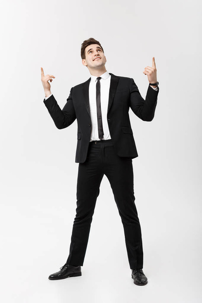 Business Concept: Handsome Man Happy Smile Young Handsome Guy in smart suit posing pointing finger over Isolated Grey Background. - Foto, imagen