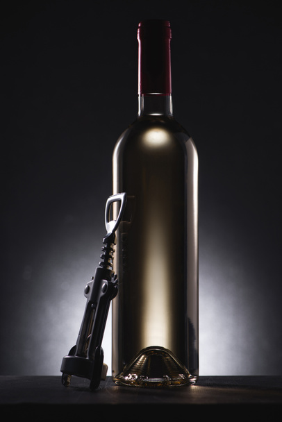 close-up shot of bottle of white wine with corkscrew on black - Foto, Imagem