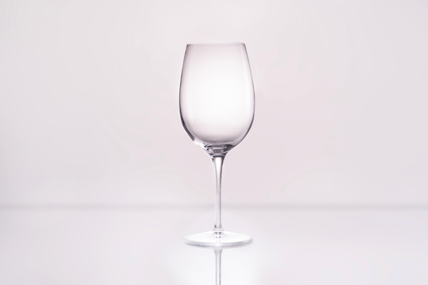 empty wineglass on reflective surface and on white - Zdjęcie, obraz