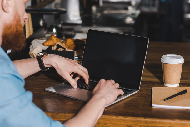 cropped image of young male barista sitting at table with laptop  - Photo, Image