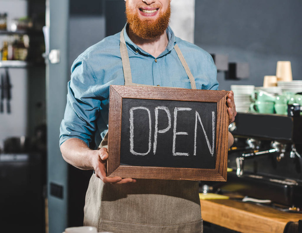 przycięte zdjęcie młodych mężczyzn barista gospodarstwa tablica z napisem otwarte w kawiarni - Zdjęcie, obraz
