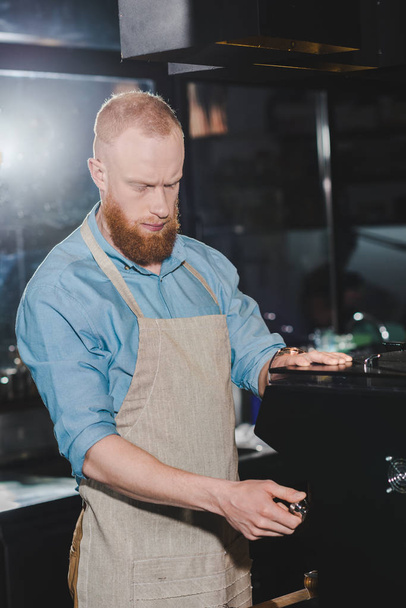 young male barista in apron using coffee machine - Foto, Bild