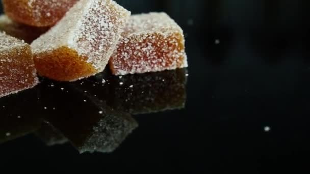 grote groep oranje marmelade stukken bedekt met suiker op zwarte spiegel achtergrond - Video