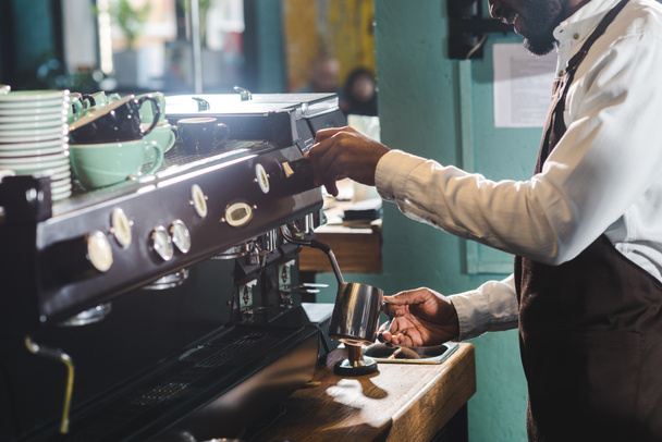 recortado disparo de sonriente africano americano barista haciendo capuchino en la máquina de café
 - Foto, Imagen