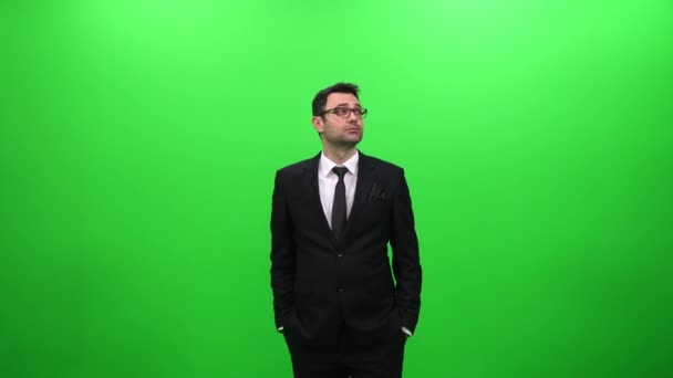 Geschäftsmann schaut sich vor grünem Bildschirm um - Filmmaterial, Video