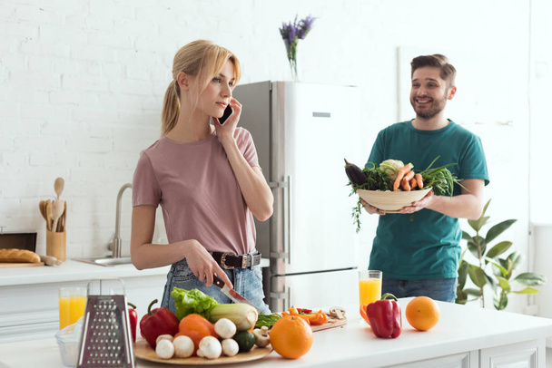 vegan girlfriend talking by smartphone while cooking at kitchen - Foto, imagen