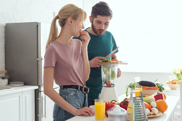 namorado preparando suco de legumes com espremedor na cozinha, conceito vegan
 - Foto, Imagem