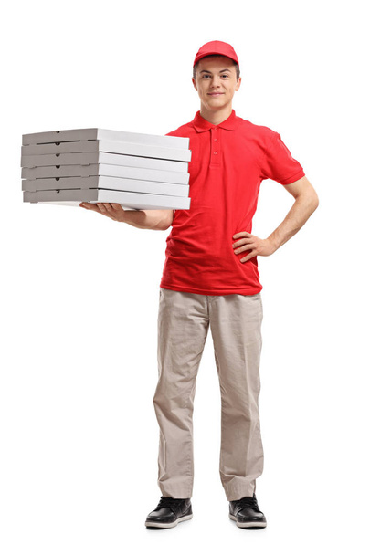 Full length portrait of a teenage delivery boy holding pizza boxes isolated on white background - Foto, Bild