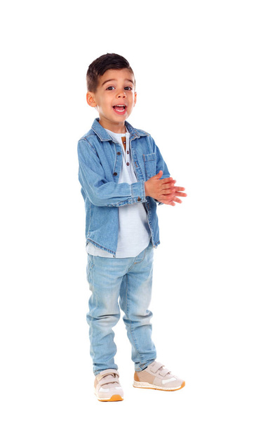hymyilevä pieni poika denim-vaatteissa ja taputtamalla kädet eristetty valkoisella taustalla, täyspitkä
 - Valokuva, kuva