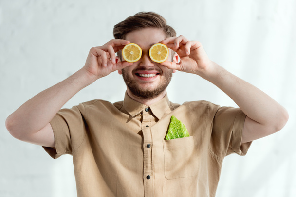obscured view of smiling man with lemon pieces and savoy cabbage leaf in pocket, vegan lifestyle concept - Zdjęcie, obraz