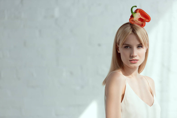 young pretty woman with red bell pepper on head, vegan lifestyle concept - Foto, imagen