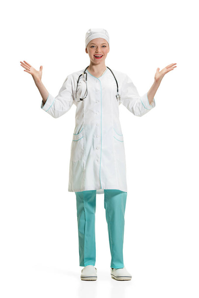 Beautiful young woman in white coat posing at studio. Full length studio shot isolated on white. - 写真・画像