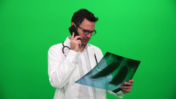 Lekarz gospodarstwa X Ray wyniki i rozmawia przez telefon na zielony ekran - Materiał filmowy, wideo
