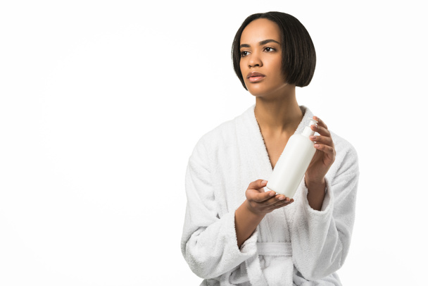 mulher africana americana em roupão de banho segurando garrafa de loção, isolado em branco
 - Foto, Imagem