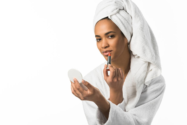 attractive african american woman in bathrobe and towel with mirror applying lipstick,  isolated on white - Φωτογραφία, εικόνα