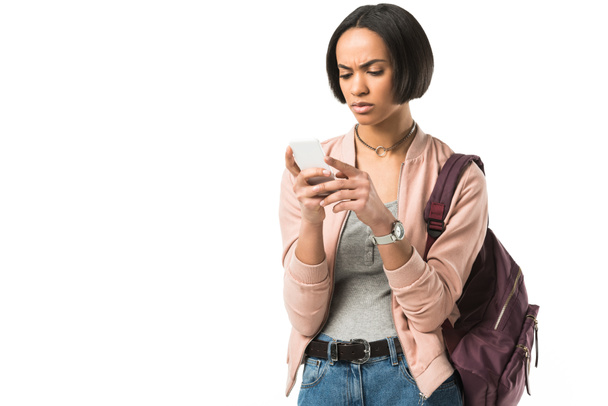 confundido estudiante afroamericano con mochila usando teléfono inteligente, aislado en blanco
 - Foto, Imagen