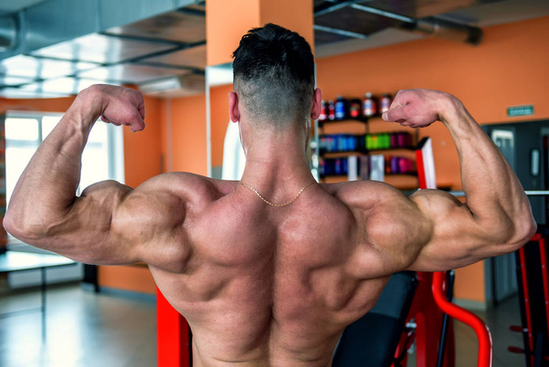 bodybuilder shows his muscular back in the gym - Foto, afbeelding
