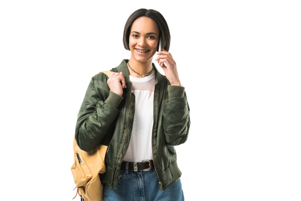 belle étudiante afro-américaine souriante avec sac à dos parlant sur smartphone, isolée sur blanc
 - Photo, image