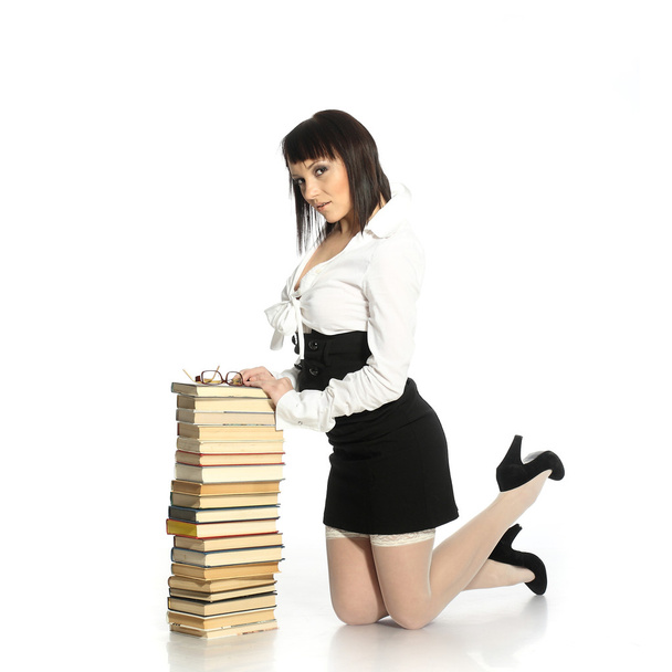 Menina atraente vestida com meias eróticas inclinando-se em uma pilha de livros
 - Foto, Imagem