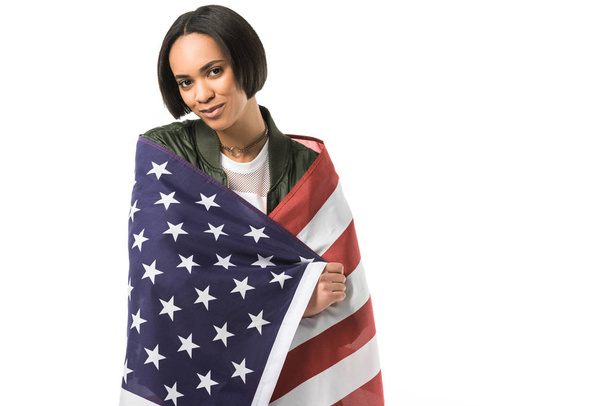 lachende Afrikaans Amerikaans meisje verpakt in Verenigde Staten vlag, geïsoleerd op wit - Foto, afbeelding