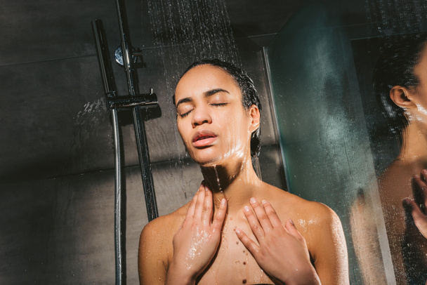 привлекательная африканская американка с закрытыми глазами принимает душ
 - Фото, изображение