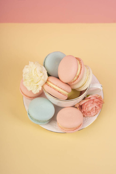 Multicolored macaroons cake are placed in a saucer and a cup alo - Zdjęcie, obraz