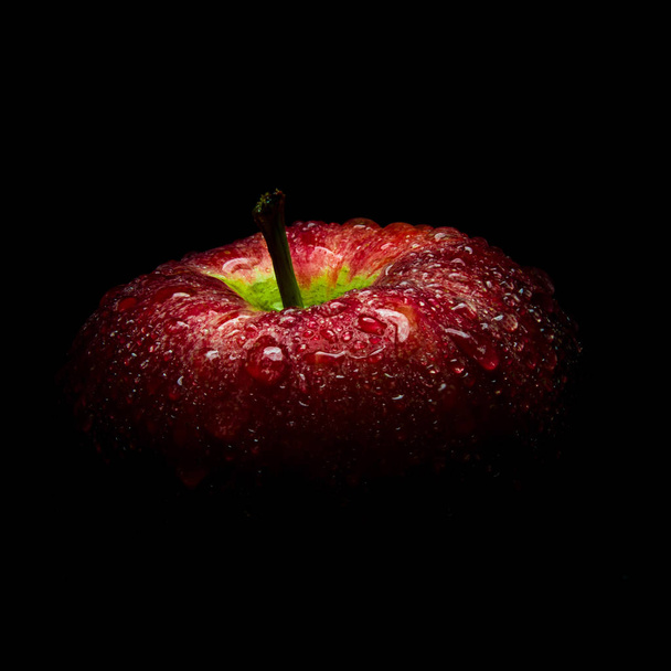 Σταγόνα νερού σε γυαλιστερή επιφάνεια σε μαύρο φόντο κόκκινο μήλο - Φωτογραφία, εικόνα