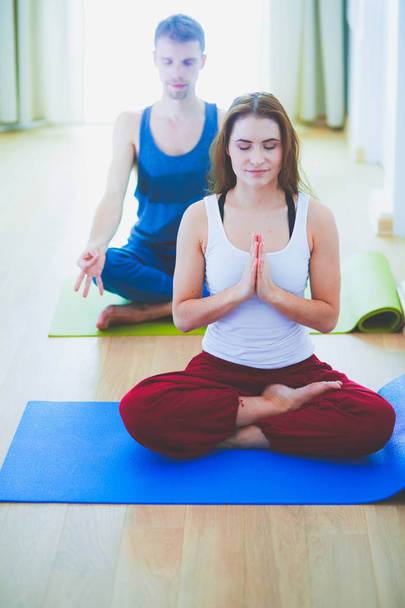 Jonge gezonde paar in yoga positie op witte achtergrond - Foto, afbeelding
