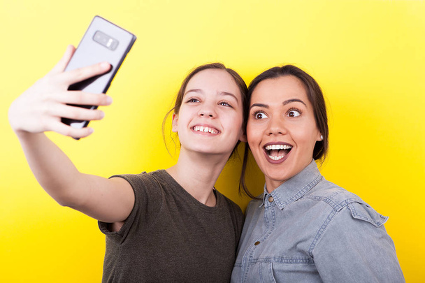 Feliz risa y sonriente hermanas tomando un selfie
 - Foto, imagen