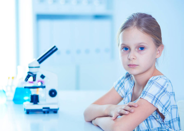 Schoolgirl looking through microscope in science class. - Foto, afbeelding