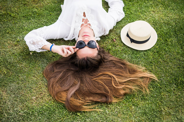 Mooie, jonge vrouw vastgesteld op gras op zomertijd - Foto, afbeelding