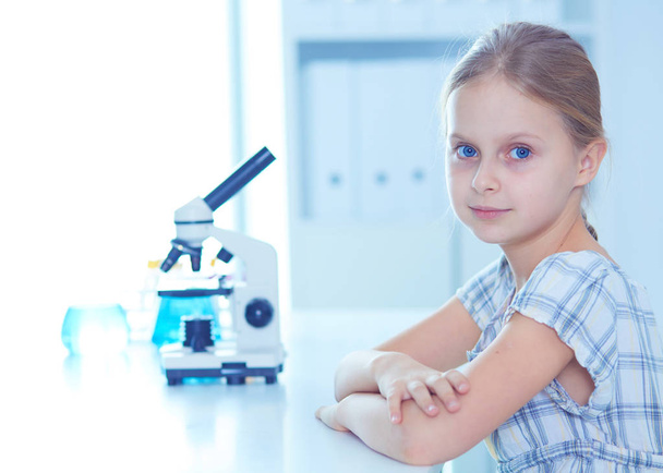 Schoolgirl looking through microscope in science class. - 写真・画像