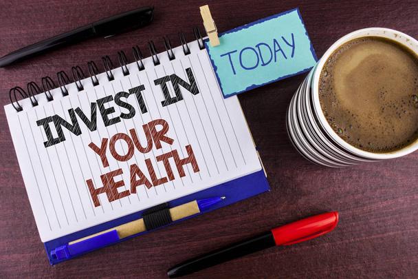 Szó szöveg írása Invest az Ön egészségét. Üzleti koncepció költ pénzt a személyes egészségügyi megelőző vizsgálatok írt a Jegyzettömb fa háttér ma klip toll Marker csésze kávé - Fotó, kép