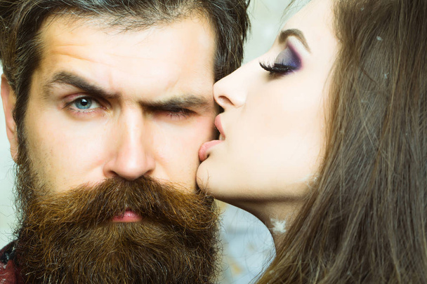 Woman kiss hipster with long beard, love. Sensual woman with makeup skin and bearded man. Couple in love and family concept. Beauty salon and barber shop. Skincare and hair care concept. - Fotoğraf, Görsel