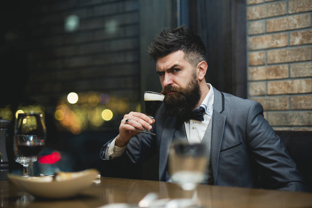 serious bearded male drinking ale in pub - Фото, изображение