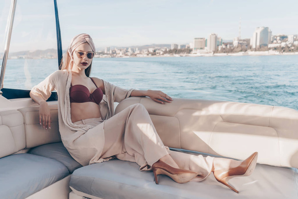 a luxurious rich woman in stylish clothes rests on her white yacht, sails to the islands on vacation - 写真・画像