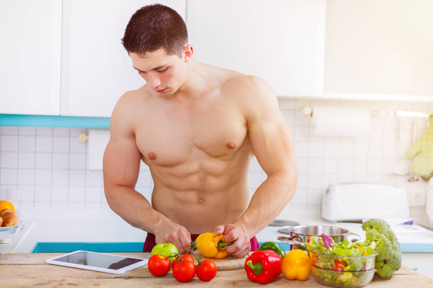 Young man cooking bodybuilder healthy meal vegetables tablet int - Fotó, kép
