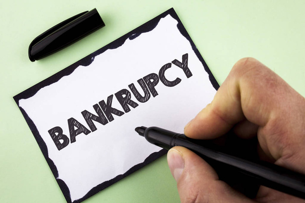 Handwriting text Bankrupcy. Concept meaning Company under financial crisis goes bankrupt with declining sales written by Man on White sticky note paper holding Marker on plain background. - Photo, Image