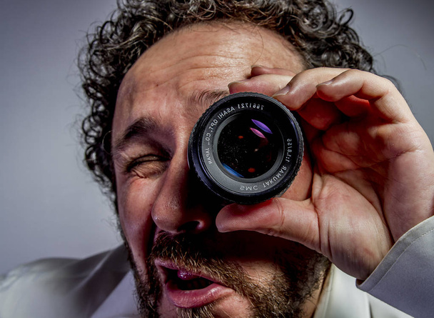photographer with lens, man with intense expression, white shirt - Zdjęcie, obraz