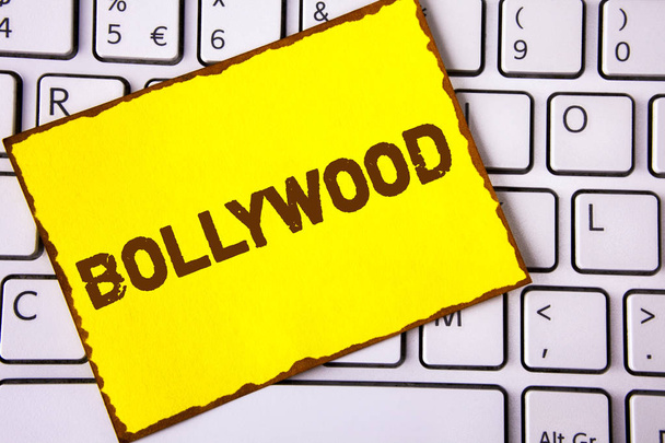 Sinal de texto a mostrar Bollywood. Foto conceitual Cinema indiano uma fonte de entretenimento escrito em papel de nota pegajosa amarelo colocado no teclado branco. Vista superior
. - Foto, Imagem