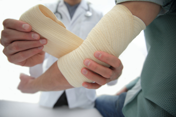 Orthopédiste appliquant un bandage sur les patients main dans la main en clinique
 - Photo, image