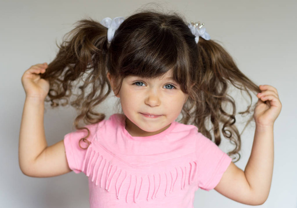 Retrato de hermosa niña divertida de cuatro años, sonriendo sobre fondo blanco, pelo largo rizado
 - Foto, imagen