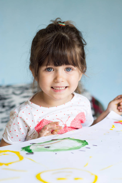 kleines Mädchen malt mit Gouache, während es am Tisch sitzt - Foto, Bild