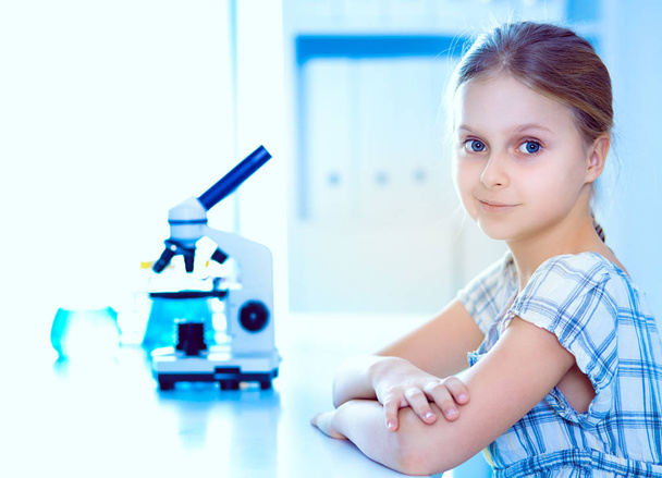 Schoolgirl looking through microscope in science class - 写真・画像