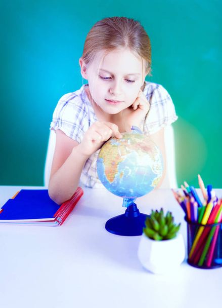 Дівчина вчиться за столом, сидячи на столі
 - Фото, зображення