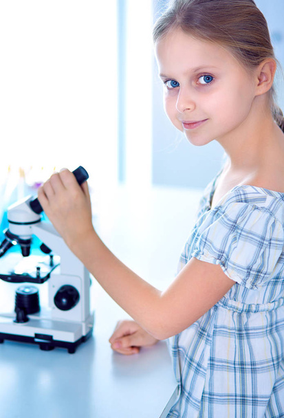 Schoolgirl looking through microscope in science class - Foto, Imagem