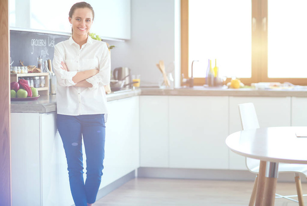 Portrait of young woman standing with arms crossed against kitchen background. Woman in the kitchen. - Fotoğraf, Görsel