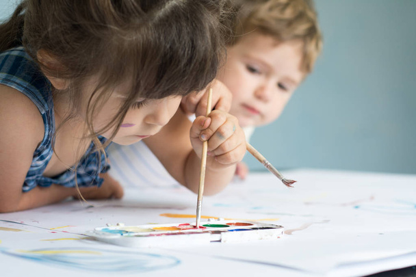 niños jugando y pintando en casa o en el jardín de infantes o en la escuela de juegos
 - Foto, Imagen
