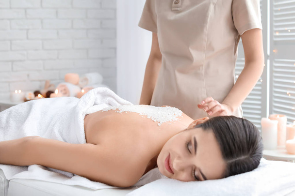 Young woman having body scrubbing procedure with sea salt in spa salon - Foto, immagini