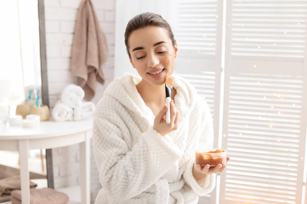 Young woman applying natural scrub on face in bathroom - Valokuva, kuva